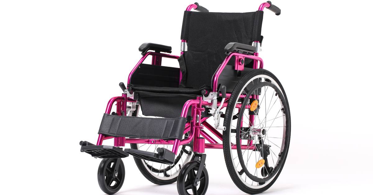 A wheelchair against a white background. The frame of the chair is customized with a metallic pink color.