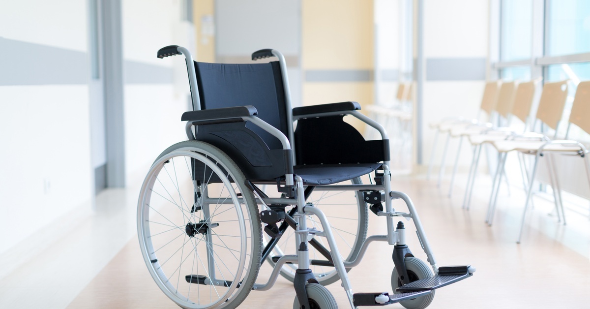 Why Breathable Fabric in Wheelchair Seat Covers Is Vital An empty wheelchair sitting in the corridor of a hospital. Behind the wheelchair is a row of basic seats along a window.