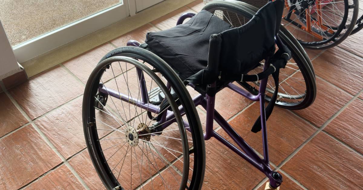 A lightweight black wheelchair with a large padded cushion on the seat to improve comfort and mobility.